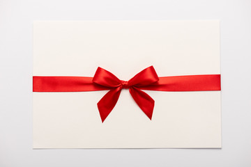 top view of red satin bow on envelope isolated on white