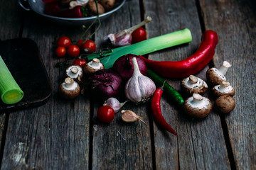 Raw vegetables  on a wooden table. Healthy nutrition. Leek, blue onion, champignons, hot pepper, sweet pepper, tomatoes