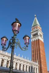 Fototapeta na wymiar Detail of lamp post and lanterns in front of San Marco Campanile or bell tower in St marks square in Venice, Italy