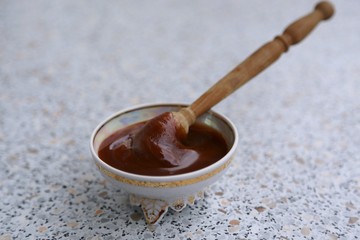 Thick honey and a spoon of wood in a glass plate 