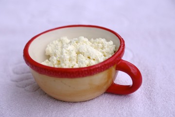Clay cup with red rim and curd white fresh inside cup side view