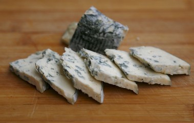 Cheese pieces with green carvings on wood board
