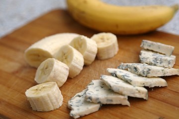 Cut cheese with mold and skin-free banana pieces ready to eat and banana .