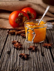 Fresh Persimmon and Persimmon jam or marmalade in glass jar  on wooden background. Close up photography.