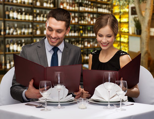 leisure and luxury concept - smiling couple with menus over restaurant or wine bar background