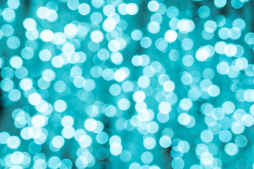 Light blue bokeh background. Turquoise color of the lights. New year backdrop. Abstract pattern of blue bokeh. Night bokeh city blurred. Beautiful illumination on Christmas tree.