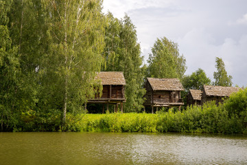 Fototapeta na wymiar Rural landscape. Sheds for storage of agricultural goods are located on the river Bank among the birches. Kostroma, Russia.