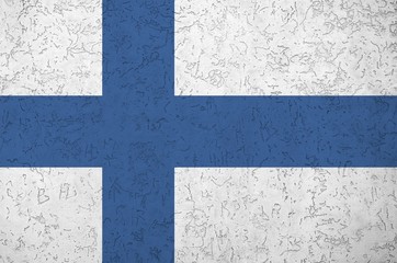 Finland flag depicted in bright paint colors on old relief plastering wall. Textured banner on...