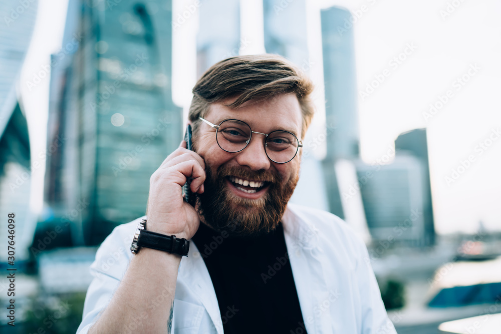 Poster close up portrait of cheerful male programmer in optical spectacles smiling at camera while receivin