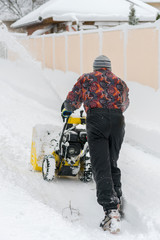 man operating snow blower to remove snow on driveway. Man using a snowblower. A man cleans snow...