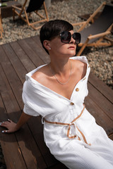 Beautiful woman with short brunette hair in white clothes and sunglasses. Fashion street...