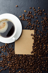 Vertical shot of cup of coffee and coffee beans, craft card for text or design on the dark surface