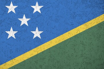 Solomon Islands flag depicted in bright paint colors on old relief plastering wall. Textured banner...