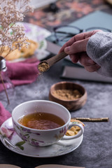 A person putting brown sugar in a cup of tea 