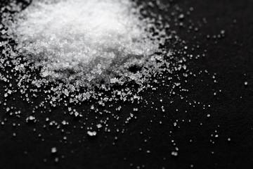 Pile of sea salt on black background. Selective focus