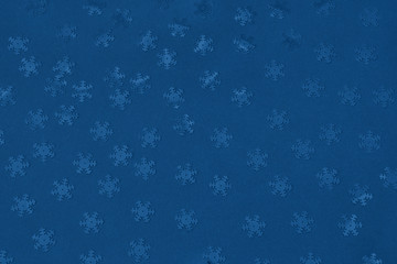 Metallic foil snowflakes confetti sparse on trendy classic blue colored background. Simple holiday concept. Winter festive backdrop. Top view, flat lay. Color of the year 2020.