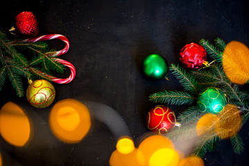 Fototapeta na wymiar Christmas or New Year decoration background: fur-tree branches, colorful glass balls on black grunge background with copy space