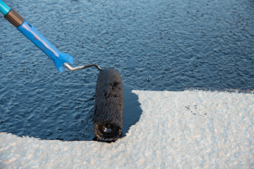 Worker applies bitumen mastic on the foundation