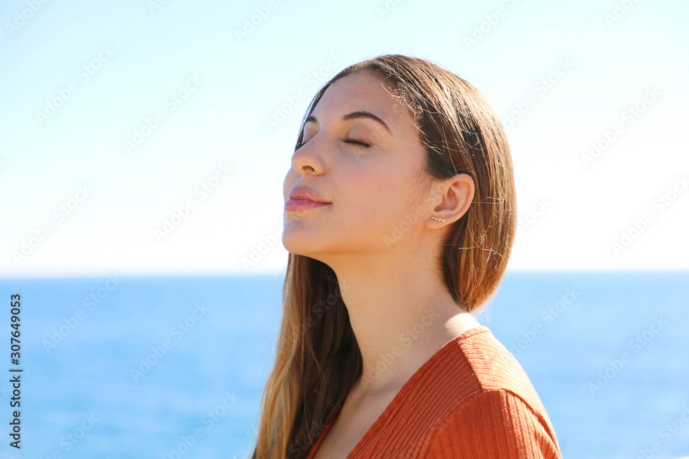 Wall mural woman profile portrait breathing deep fresh air on the beach with the ocean on background.