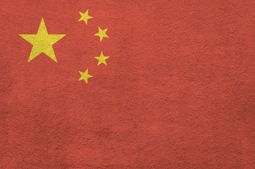 China flag depicted in bright paint colors on old relief plastering wall. Textured banner on rough...