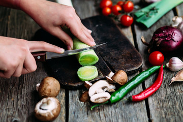 Female hands cut vegetables on the board. Cooking vegetarian food.