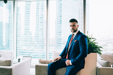 Confident businessman with smartphone looking at camera