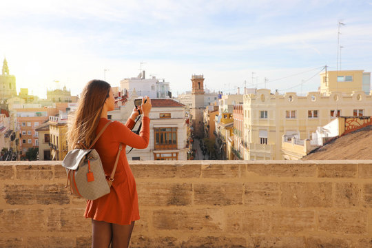 Back view of traveler girl taking picture from terrace of Valencia cityscape, Spain.