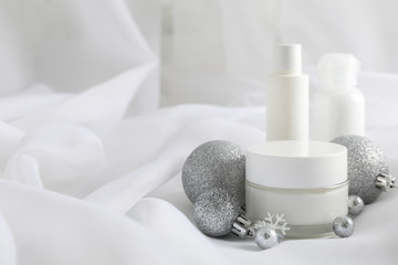 Fototapeta na wymiar Set cosmetics, jar of winter cream for skin on white fabric background, closeup. Top view