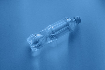 Clear plastic bottle on classic blue background colored in trendy color