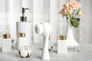 Modern face cleansing brush on light grey marble table. Cosmetic accessory
