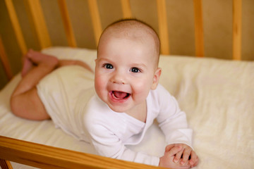 Portrait of a beautiful infant baby boy 5 months old in white clothes, sleeping in his crib. Childhood dreams. Concept of health and children. Selective focus.