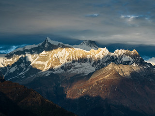 Sunset overlooking the majestic Himalayan peaks - Annapurna IV and Annapurna II, covered with clouds illuminated by the sunset.