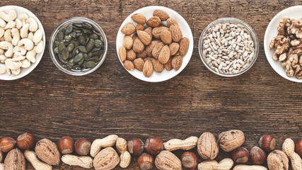 Holzhintergrund mit mehreren Sorten an Nüssen und Kernen matt