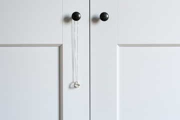 White wardrobe doors with a hanging necklace with silver heart pendant. Minimalistic style.