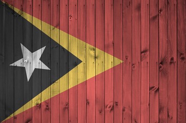 Timor Leste flag depicted in bright paint colors on old wooden wall. Textured banner on rough...