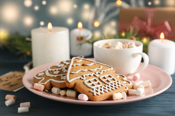 Plate of homemade Christmas cookies, coffee, marshmallows on wooden table, against blue background, space for text. Closeup