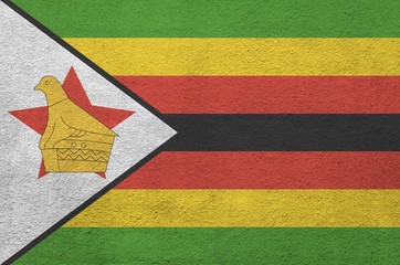 Zimbabwe flag depicted in bright paint colors on old relief plastering wall. Textured banner on...