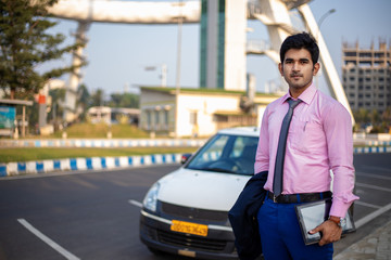 Young Indian businessman with tablet in hand standing near car , Businessman and Employee concept