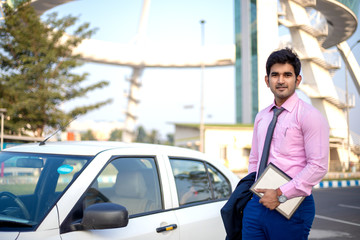 Young Indian businessman with tablet in hand standing near car , Businessman and Employee concept