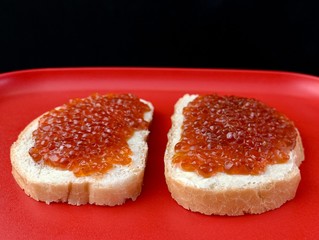 Sandwiches with red caviar, closeup. Bread with butter and fish caviar on a tray. Festive treat on the table.