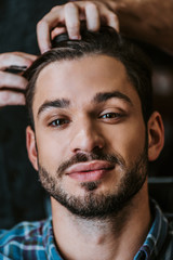 Fototapeta premium barber with black hair pomade on hands styling hair of bearded man