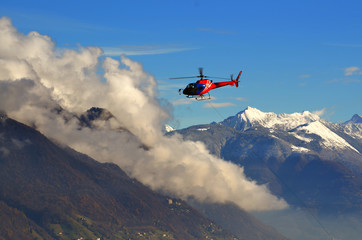 Flying Helicopter with Clouds and Snow-capped Mountain in Switzerland.