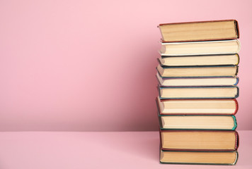 Stack of hardcover books on pink background. Space for text