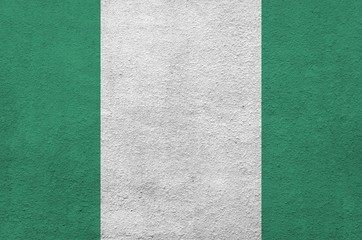 Nigeria flag depicted in bright paint colors on old relief plastering wall. Textured banner on...