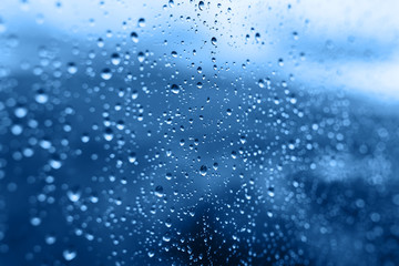 Fototapeta na wymiar Blurred raindrops on the glass background Classic blue color 
