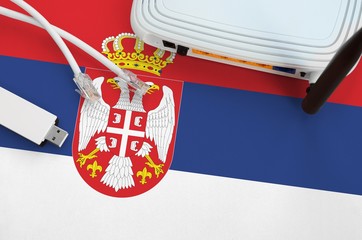Serbia flag depicted on table with internet rj45 cable, wireless usb wifi adapter and router....