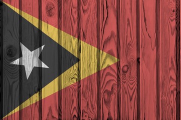 Timor Leste flag depicted in bright paint colors on old wooden wall. Textured banner on rough...