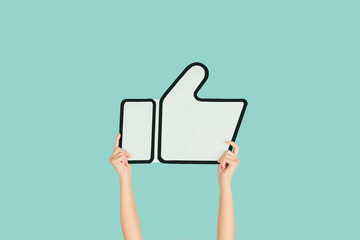 Hands holding the sign of like on blue studio background. Negative space to insert your text or...