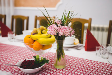 Bukiet kwiatów, sałatka i patera z owocami na stole
