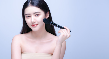 Beauty Asian Girl with Makeup Brushes. She smiling and looking to camera with powder brush, Natural makeup with beautiful v-shape face like korean style